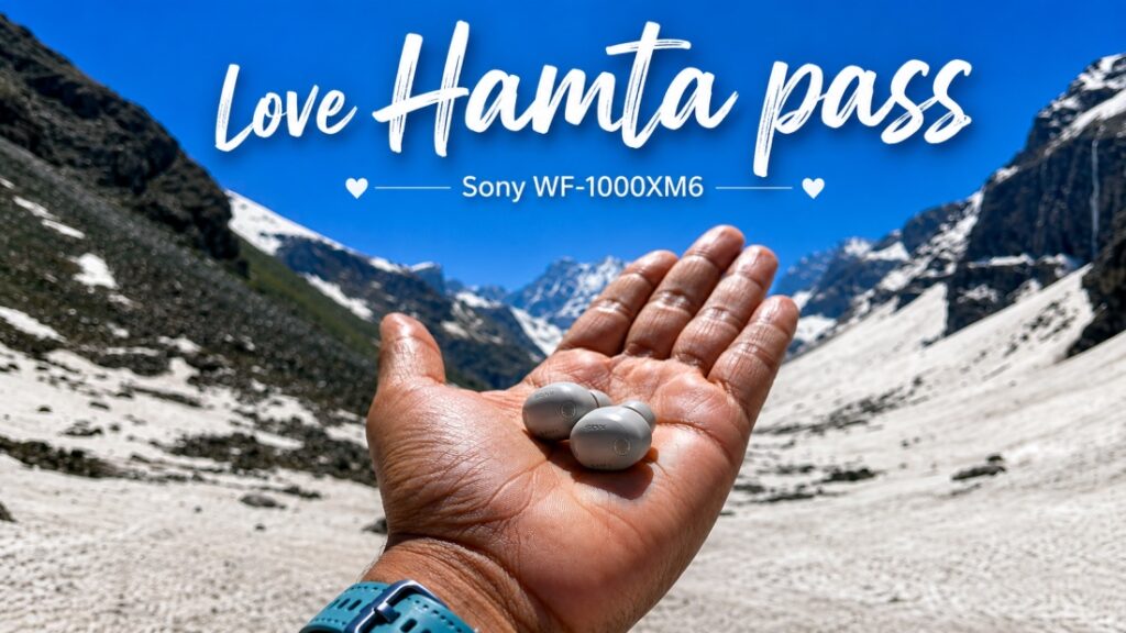 “Sony WF-1000XM6 earbuds held in a traveler’s palm at Hamta Pass, surrounded by snow-covered Himalayan mountains.”